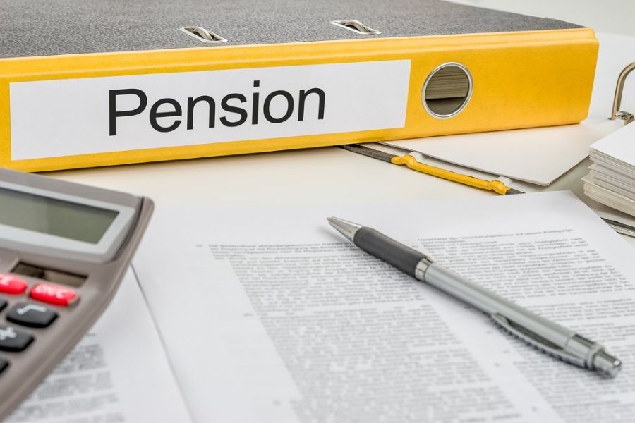 Yellow folder with Pension label next to a pile of papers and pens